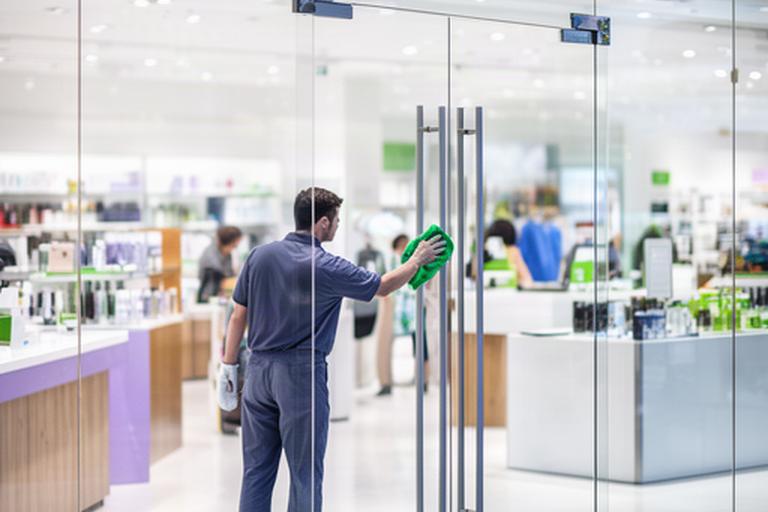 Cleaner wiping glass doors in a high-traffic Oceanside retail storefront